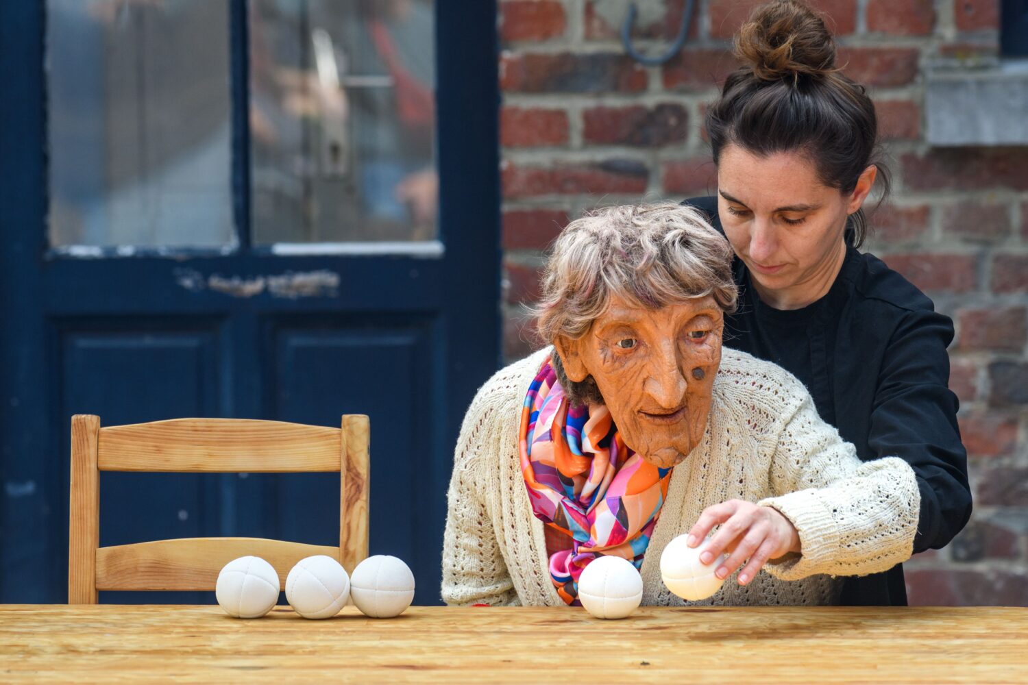 Photographie du spectacle Claudette. Claudette et la marionnettiste placent des balles sur une table.